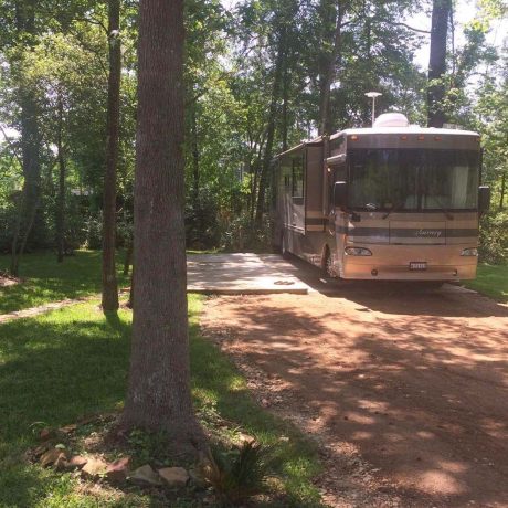 parked RV surrounded by grass and trees